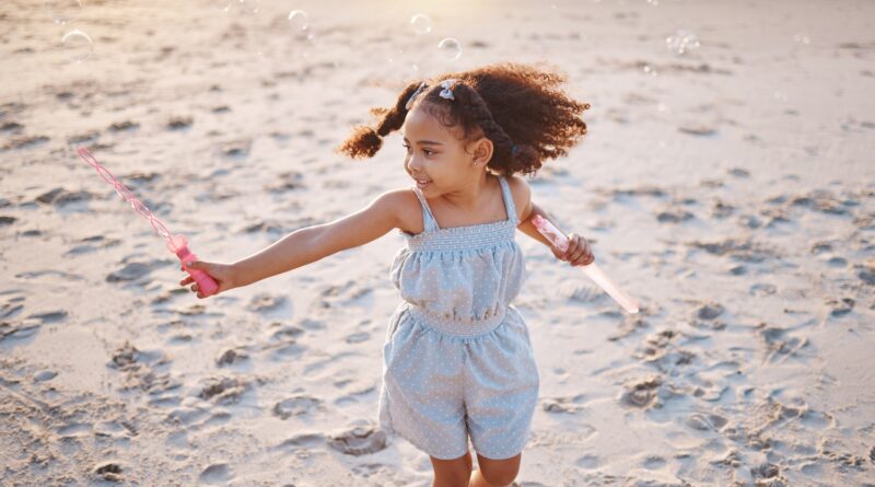 Girl child, beach and outdoor with bubbles, playing and freedom on sand, games and smile in nature.