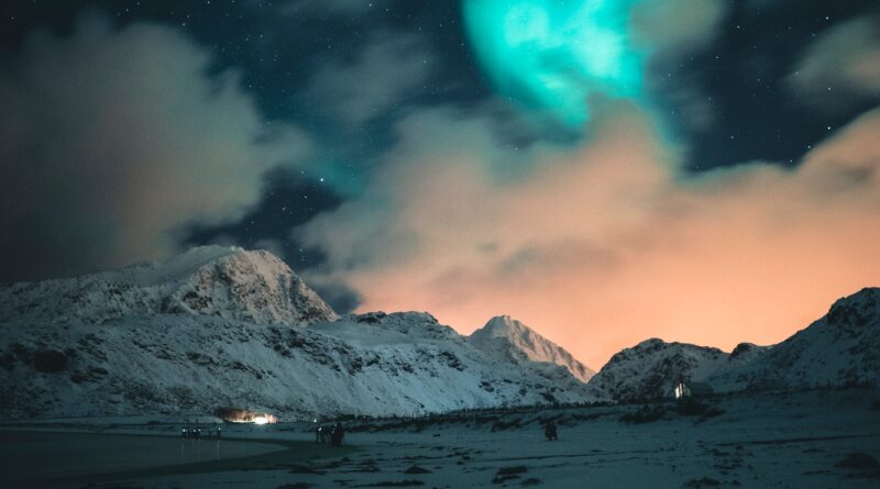 Northern lights illuminating snowy mountains in lofoten islands, norway