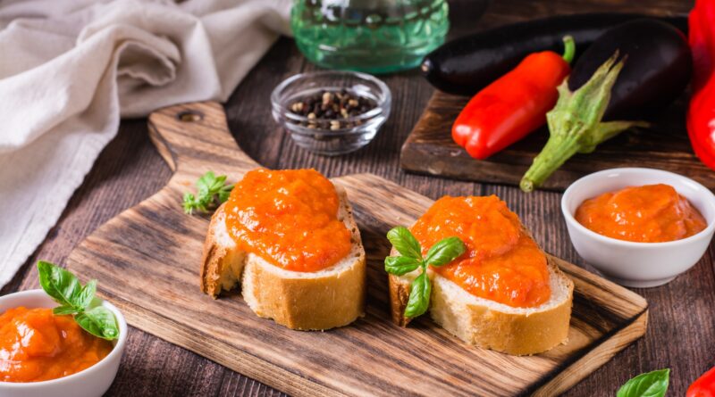 Spicy appetizer ajvar on pieces of bread and in bowls on the table