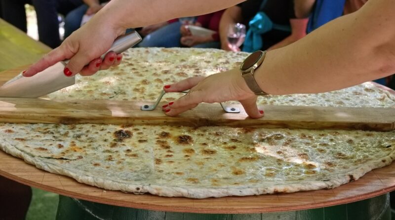Womans hands cutting soparnik - traditional Croatian food on big wooden plate